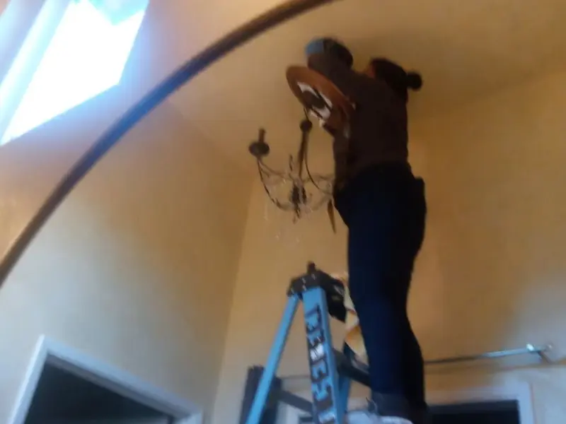 Electrician installing a chandelier in a South Heidelberg residence